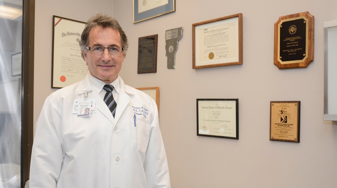 Dr. Christian Guier in his office beside his framed diplomas and awards